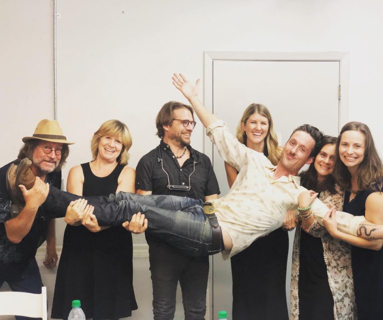 group of adults holding a man horizontally
